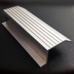 Metal bracket with ridged surface on black.