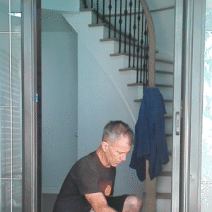 Man installing screen door in doorway.