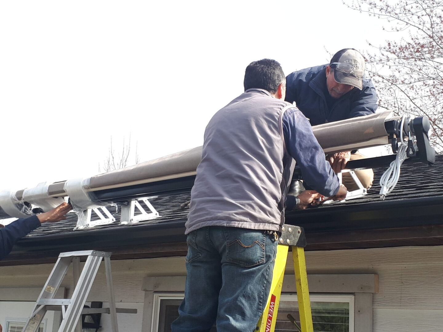 black-and-tan-retractable-awning-installation-on-roof